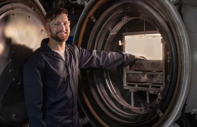 IperionX employee in front of a furnace used to produce 100% recycled titanium metal powder with the potential to use all-renewable power